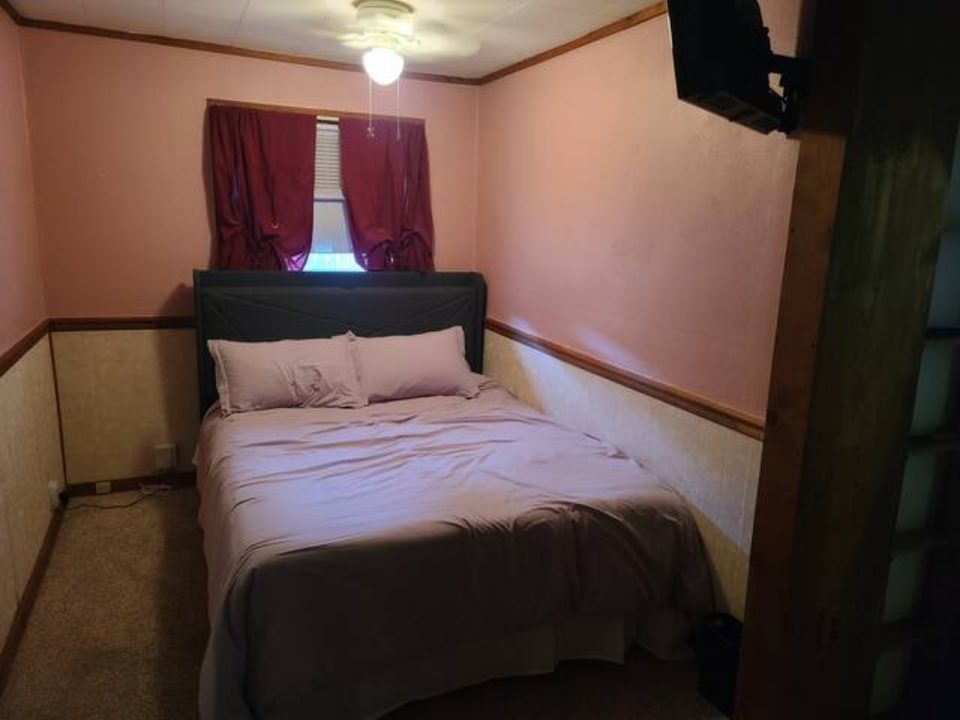 Main bedroom with a queen bed and burgundy curtains
