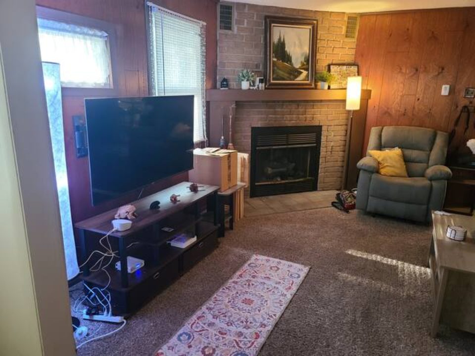 Living room with 50-inch TV, brick fireplace, and recliner